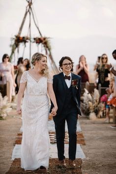 a bride and groom walking down the aisle at their outdoor wedding ceremony with guests in the background