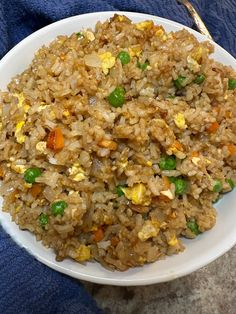 a white plate topped with fried rice and veggies next to a blue towel