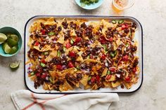 nachos on a tray with salsa and limes