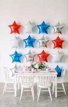 a white table topped with red, white and blue stars next to a wall filled with balloons