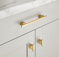 a white cabinet with brass handles and knobs on the front door, next to a marble countertop