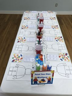 a long table is decorated with legos and paper plates for the kids to make