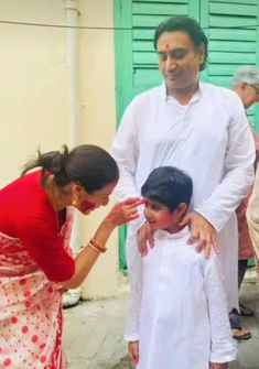 a woman standing next to a little boy in front of a green door with his face painted white