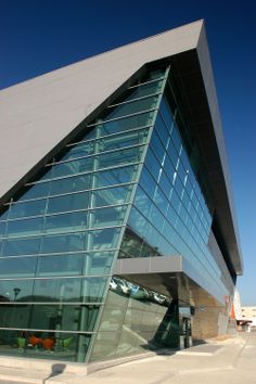 a large glass building sitting on the side of a road next to a parking lot