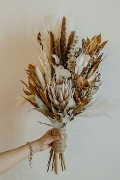 a person holding a bunch of dried flowers