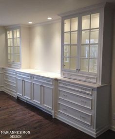 an empty kitchen with white cabinets and wood flooring in the middle of the room