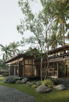 the house is surrounded by lush green trees and rocks, along with large stones on the ground