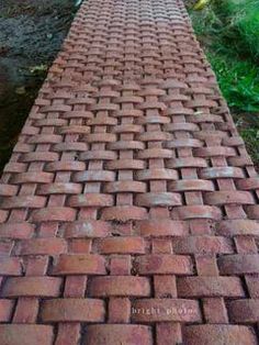 a red brick walkway with grass and trees in the background