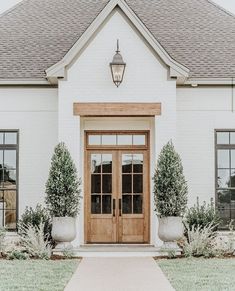 a white brick house with two large planters on the front and one door open