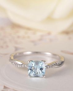 a ring with an aqua blue topazte surrounded by white diamonds on a table