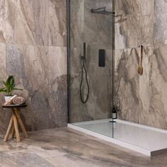 a walk in shower sitting next to a wooden table with a potted plant on it