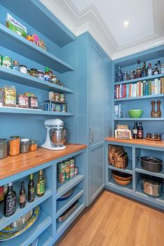 a kitchen with blue walls and shelves filled with various items on top of wooden counter tops