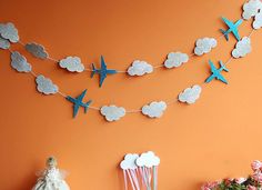 an orange wall with paper airplanes hanging from it's sides and clouds on the side