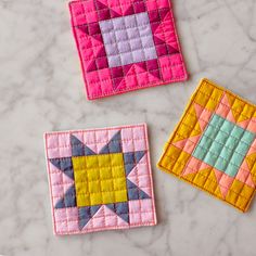 three patchwork coasters sitting on top of a marble counter