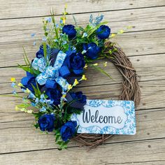 a wreath with blue flowers and welcome sign