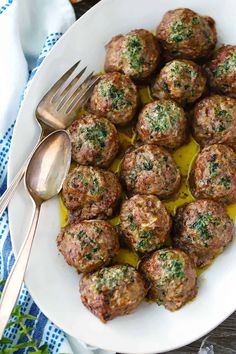 a white plate topped with meatballs covered in sauce and garnished with parsley