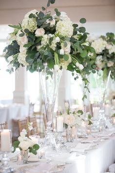 there are many vases with flowers and candles on the table at this wedding reception