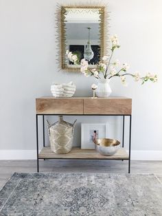 a table with vases and flowers on top of it in front of a mirror