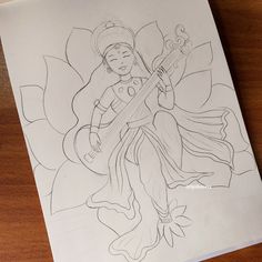 a drawing of a woman holding a guitar on top of a wooden table next to a piece of paper