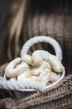 a white basket filled with powdered sugar covered donuts