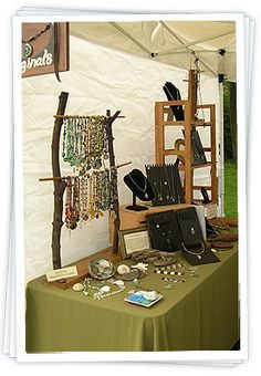 a table topped with lots of jewelry under a white tent covered by a green tarp