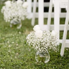 white flowers are in vases on the grass