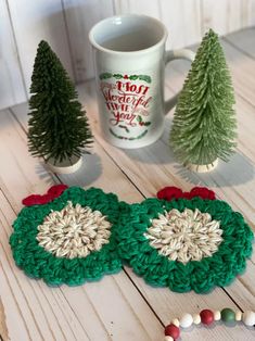 two crocheted coasters sitting on top of a table next to a coffee mug