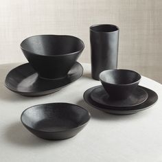 black dishes and cups sit on a white table