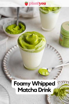 two cups filled with green whipped matcha drink on top of a white tablecloth