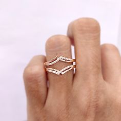 a woman's hand holding a gold ring with two rows of diamonds on it