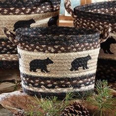 three woven baskets with black bears and pine cones on the ground next to some logs