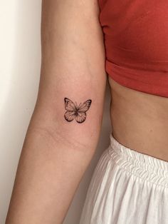 a woman's arm with a small butterfly tattoo on the back of her left arm