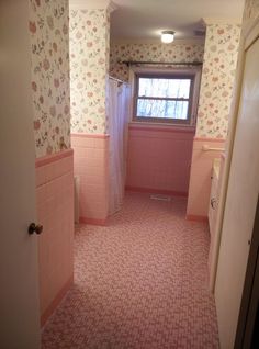 a bathroom with pink tile and floral wallpaper on the walls, along with a window