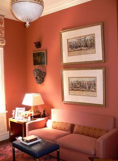 a living room with pink walls and pictures on the wall