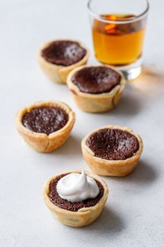 mini chocolate pies with whipped cream on top and a glass of tea in the background