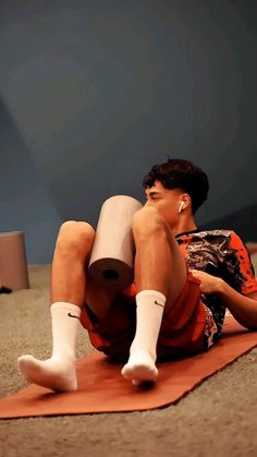 a young man sitting on top of a yoga mat while holding a white object in his hand