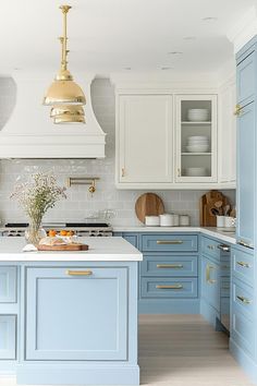 a kitchen with blue cabinets and white counter tops, gold accents on the hoods