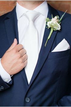 a man wearing a suit and tie with a boutonniere on his lapel