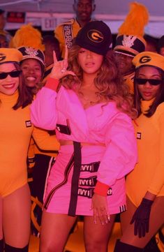 a group of women in pink outfits standing next to each other with one woman giving the peace sign