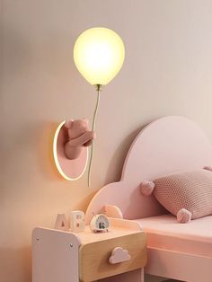 there is a light that is on the wall next to a bed with a pink headboard