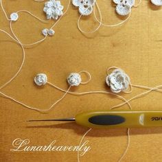 a crochet hook is hooked up to some thread and yarn with flowers on it