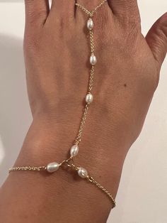 This genuine Pearl hand chain is Stunning and made by hand using genuine Swarovski rhinestones and crystals, 14k gold fill chain and clasp. Made for the Ti Adora by Alvina Valenta 2016 NY Bridal Market and LookBook photoshoot. Typical made for a 7" long hand (wrist to top of center finger):6.5" in wrist circumference with .5" additional adjustable clasp.3" from wrist up to the ring2.5" in ring loop circumference (non adjustable)Custom length is welcome! Just write in the measurements in the note Bracelet Connected To Ring, Ring To Bracelet Jewellery, Elegant Metal Jewelry With Beaded Chain, Pearl Bracelet With Pearl Drop, Party Jewelry With Adjustable Chain And Round Beads, Gold Plated Silver Jewelry With Pearl Charm, Pearl Drop Bracelet Jewelry, Silver Gold Plated Jewelry With Pearl Charm, Adjustable Metal Pearl Chain Bracelet