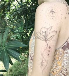 a woman with a tattoo on her arm is standing in front of some trees and bushes