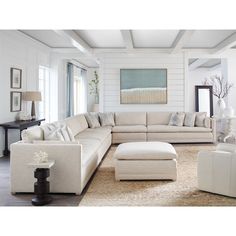 a living room filled with white furniture and lots of pillows on top of the couches