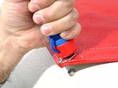 a hand holding a blue and red object in it's right hand, on top of a red surface