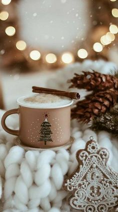 a cup of hot chocolate with cinnamon stick and christmas tree ornament next to it