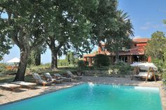 an outdoor swimming pool surrounded by trees and lawn chairs