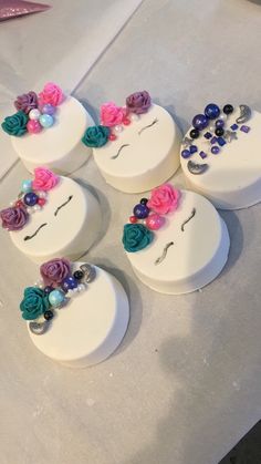 six decorated cakes sitting on top of a white table covered in beads and flowers next to each other