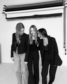 three women standing next to each other in black and white