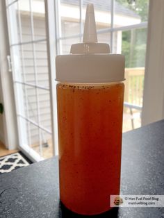 a glass jar filled with liquid sitting on top of a counter next to a window